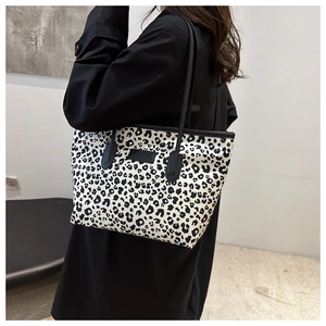 Detailed view of leopard print tote bag with black shoulder straps on model shoulder