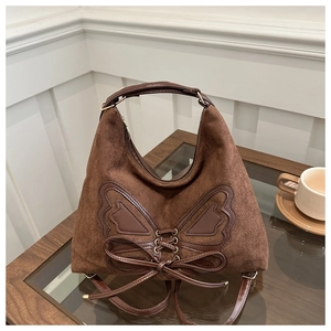 Close-up of brown suede hobo bag with a dark leather butterfly applique and bow detail