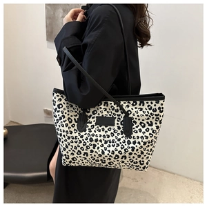 Macro detail of high-capacity leopard print tote bag with black strap on shoulder