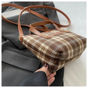 Detail showing the brown plaid fabric texture and leather strap of the tote bag