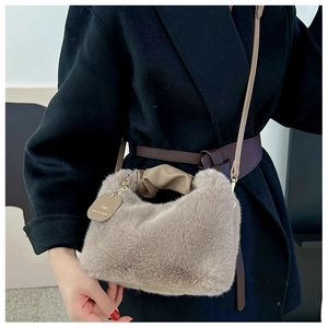Detail of khaki faux fur tote with ruched handle and golden engraved tag on black coat