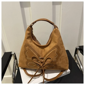 Detailed view of brown suede hobo bag featuring butterfly applique and lace-up design