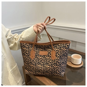 Detail of canvas leopard print tote bag featuring brown leather straps and spacious interior