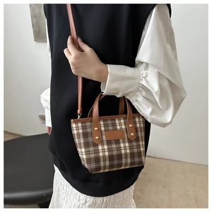 Chic brown plaid handbag with leather straps and detachable shoulder strap on model