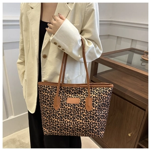 Close-up of leopard print tote bag with brown leather straps worn by a model