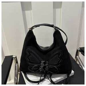 Close-up of black suede butterfly handbag with leather lace-up details and metallic eyelets