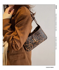 Leopard print underarm bag with gold metal buckle and adjustable strap shown on model