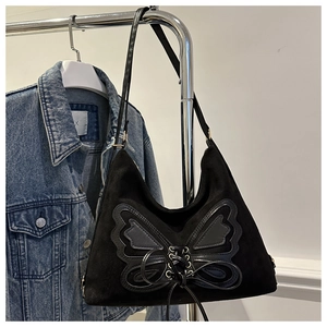 Detail of black suede hobo bag with large butterfly patch and crisscross lace-up design