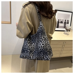 Detail of large leopard print tote bag on shoulder showing fabric texture and capacity
