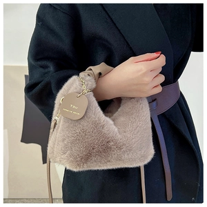 Close-up of faux fur handbag in light brown with gold chain and leather tag detail