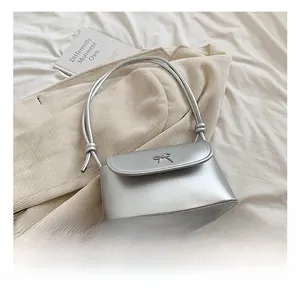 Close-up of a silver bow buckle on a metallic crossbody bag with thin shoulder straps