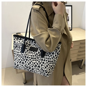 Macro detail of high-capacity tote bag featuring black and white leopard print and black straps