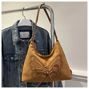 Detail of vintage brown suede tote bag with leather butterfly patch and lacing