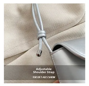 Detail of adjustable silver shoulder strap with metallic knots and cylindrical hardware