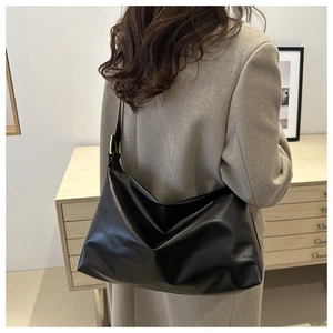 Vue détaillée d'un grand sac cabas noir porté avec une veste de costume grise chic