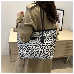 Detail of large leopard print tote bag styled on model with trench coat for casual look