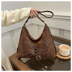 Detail of dark brown suede hobo bag with butterfly leather patch and lace-up design