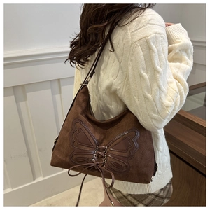 Detail view of brown suede tote bag with butterfly stitching on a model's shoulder