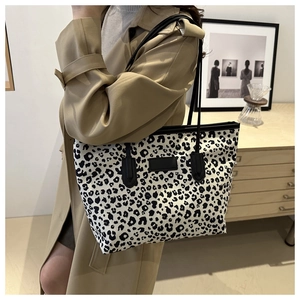 Detailed view of leopard print tote bag styled with a beige trench coat in a modern interior