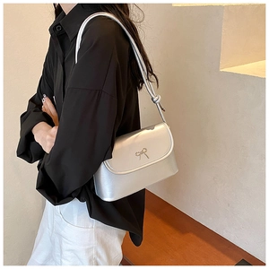 Détail du sac à bandoulière argenté métallisé avec nœud en métal et sangle nouée