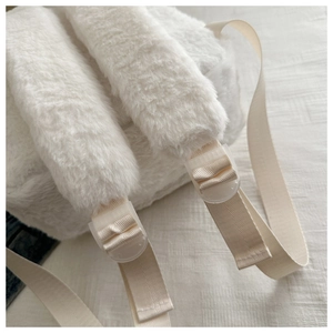 Detail of white plush backpack showing soft faux fur texture and woven shoulder strap