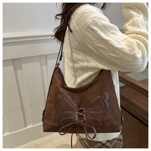Detail of a dark brown suede bucket bag with leather butterfly patch and lacing details