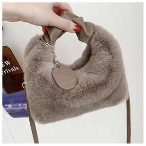 Détail du sac à main en peluche avec poignée en cuir foncé et chaîne dorée chic
