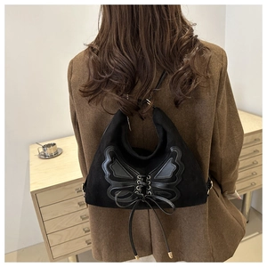 Detail of a black vintage butterfly tote bag worn by a model in a brown blazer jacket