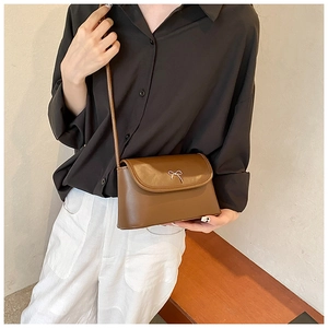 Détail du sac bandoulière en similicuir caramel avec une boucle noeud en métal argenté