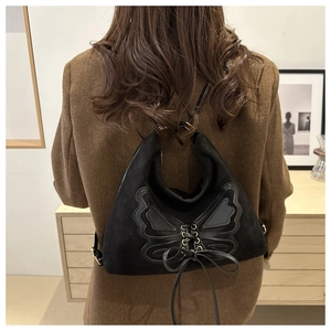 Detail of vintage black suede backpack featuring a 3D butterfly bow and lace-up design
