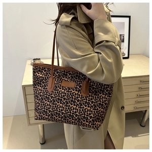 Detail of leopard print tote bag styled with a trench coat in a minimalist home setting