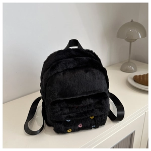 Close-up of black plush backpack with colorful buttons and red embroidery details