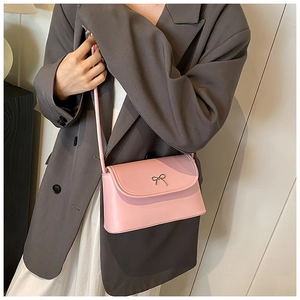 Pink PU leather square bag with metal bow detail worn over the shoulder by a model
