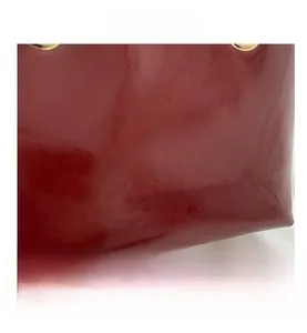 Close-up of red patent leather bucket bag with gold metal rings and embossed logo