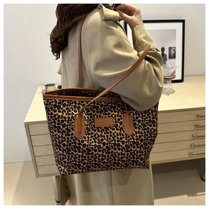 Lifestyle view of leopard print tote bag with brown leather straps on a model's shoulder