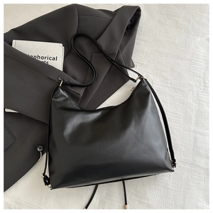 Macro view of a black large-capacity PU leather hobo bag with sleek gold hardware detail