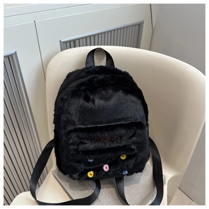 Nahaufnahme eines schwarzen Plüschrucksacks mit FASHION-Stickerei und bunten Punkten