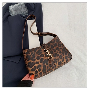 Detail view of leopard print shoulder bag featuring gold buckle on blue blazer backdrop