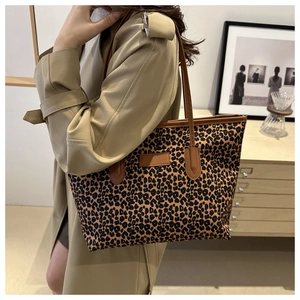 Detailed shot of a large leopard print tote bag with brown leather straps on a model