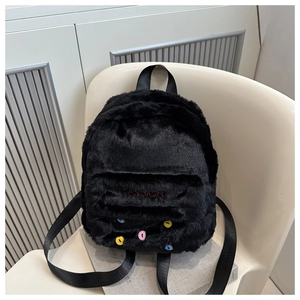 Detail eines schwarzen Plüschrucksacks mit FASHION-Stickerei und bunten Knopfakzenten