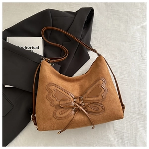 Detailed close-up of brown faux suede bucket bag with leather butterfly patchwork and laces