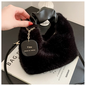 Détail du sac à main en fausse fourrure noire avec poignée froncée et pendentif doré