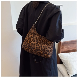 Detail of leopard print crossbody bag with gold chain strap on a black coat outfit