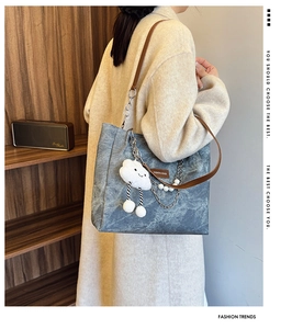 Detail of blue textured tote bag with metal chain, pearls and cloud plush charm