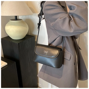 Elegant black leather crossbody bag featuring a delicate silver metal bow detail