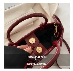 Detail showing high-gloss burgundy leather texture and secure golden magnetic snap closure