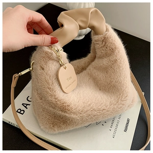 Détail du sac en fausse fourrure beige avec poignée froncée et breloque dorée
