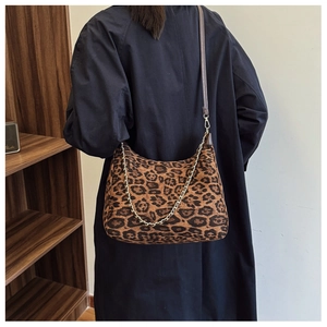 Detail showing leopard print shoulder bag texture with metal chain and slim leather strap