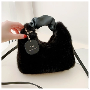 Détail du sac à main en peluche noire avec anse froncée et pendentif à chaîne dorée