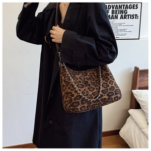 Fashionable leopard print crossbody bag with gold chain strap shown on black trench coat